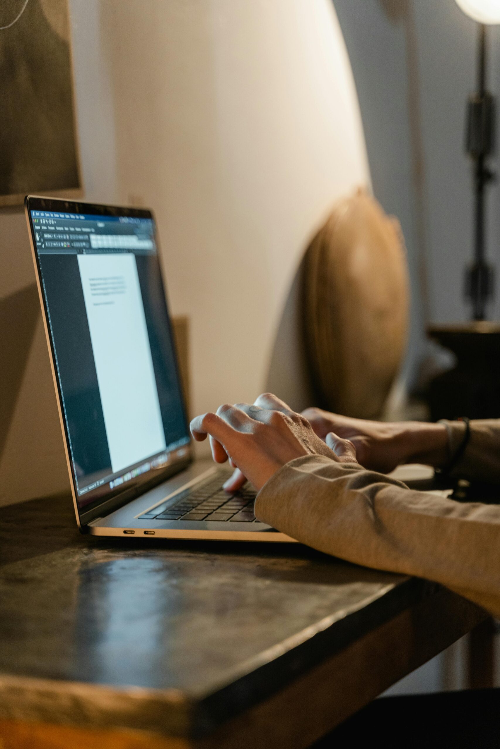 Close-up of hands typing on a laptop in a warm, cozy indoor environment. Ideal for business and technology themes.
